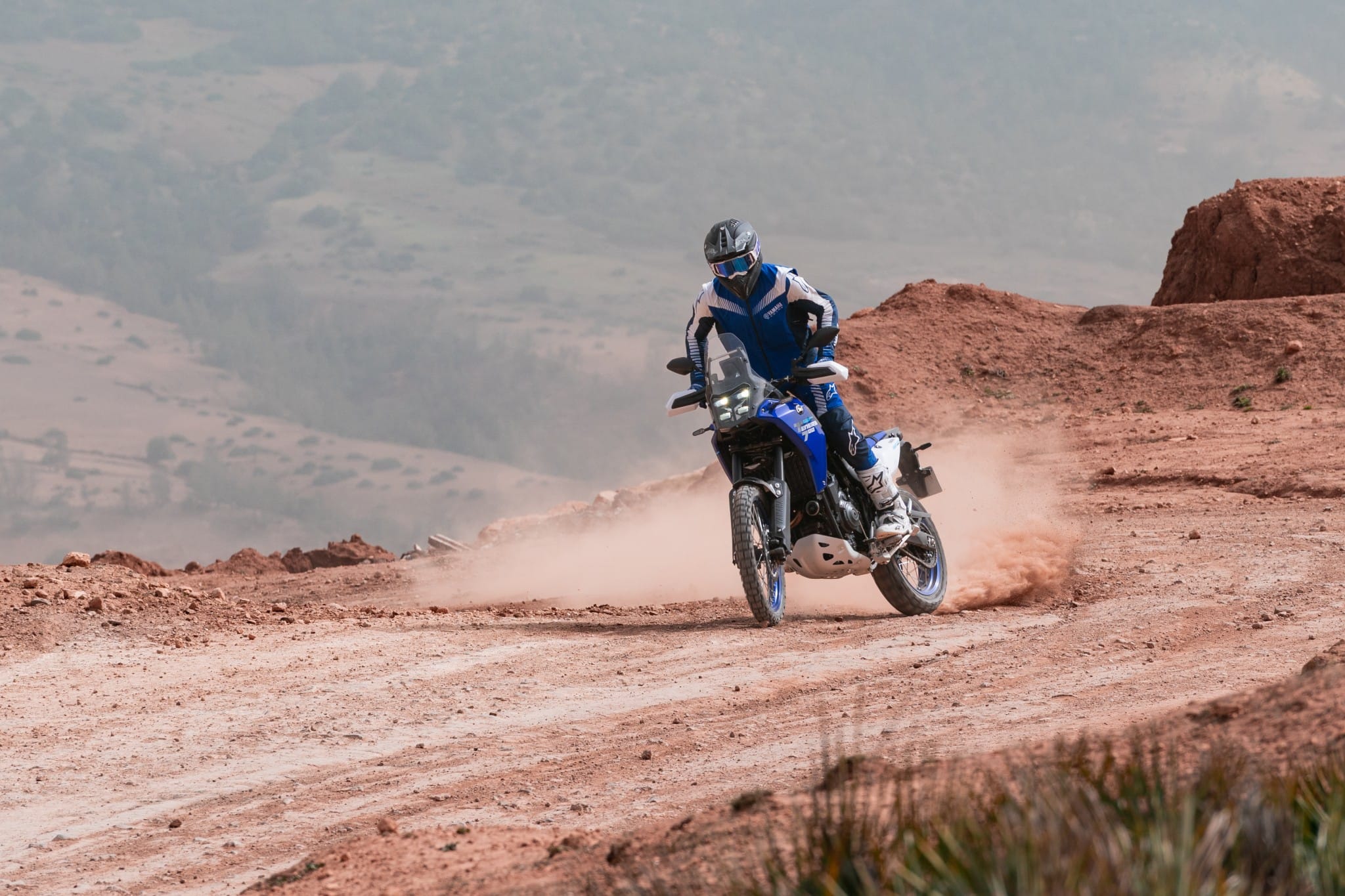 Yamaha Ténéré 700 trailing dust on a red gravel road in Morocco