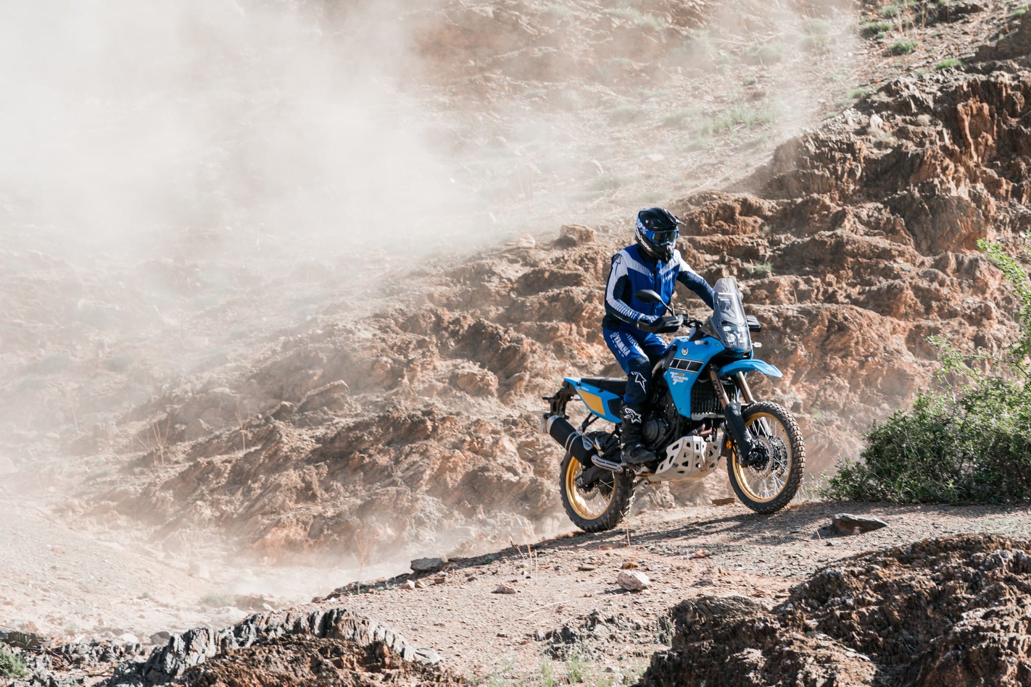 Rider jumping the Yamaha Ténéré 700 through a dusty rock gully