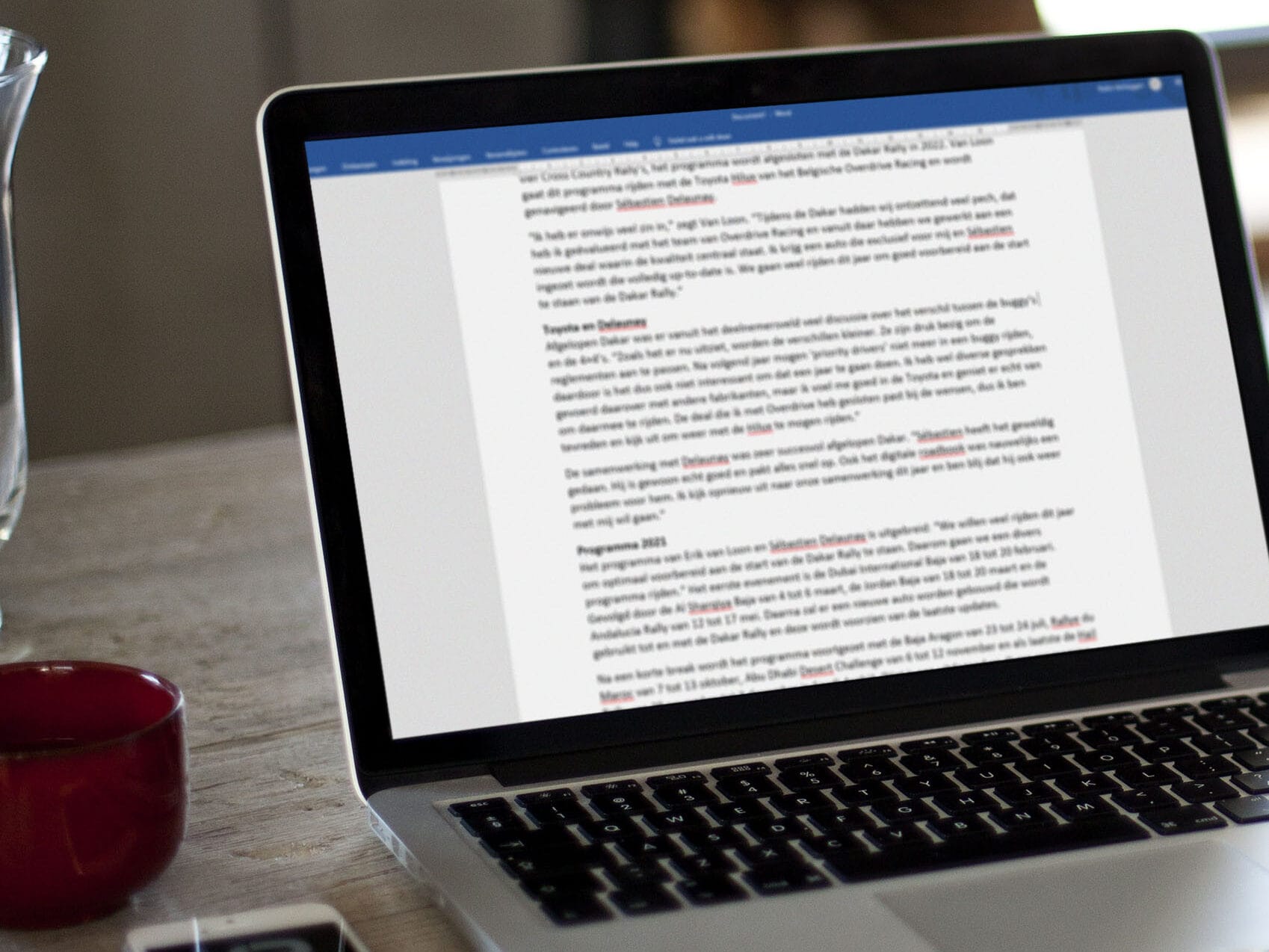 Laptop on a wooden table with a press release open for editing